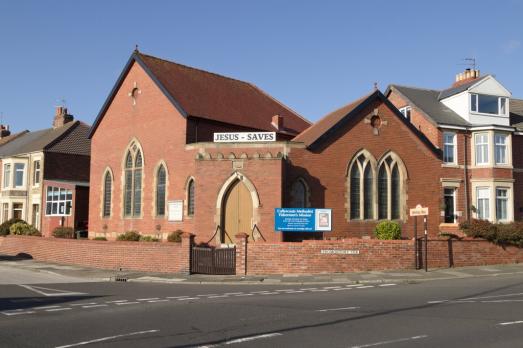 A brick church pictured from the far side of a road