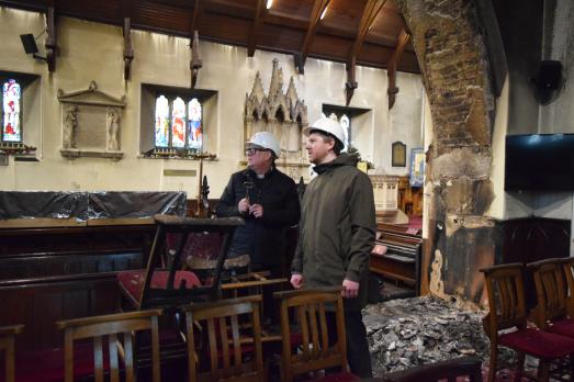 Two men in hard hats inspecting the interior of a burned out church