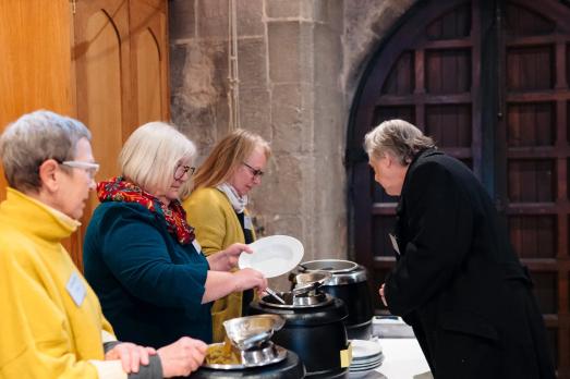 Three people serve soup inside a church