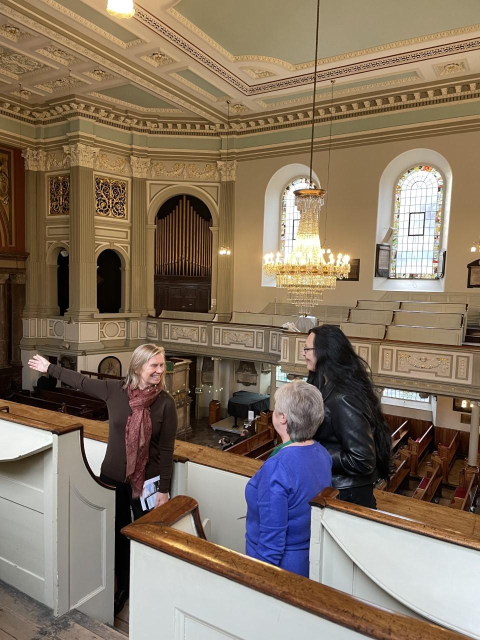 Three people standing in the gallery in a church