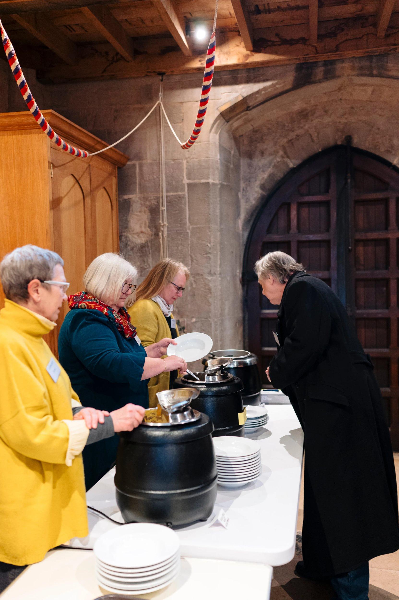 Three people serve soup inside a church