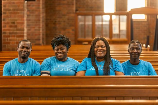 Four people sit on a pew, facing the camera, in RCCG Church, Edinburgh