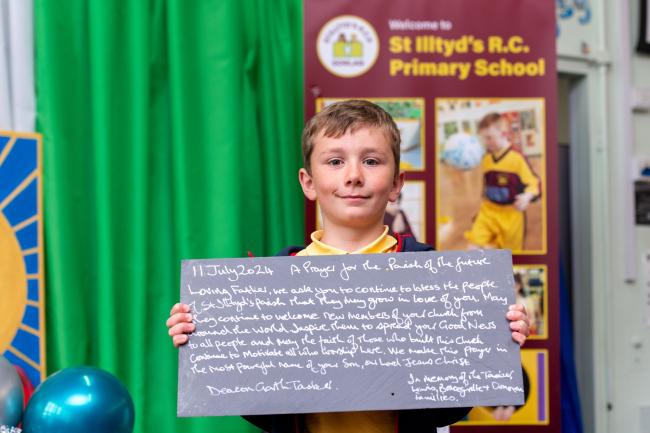 A boy holding a slate with white text on it