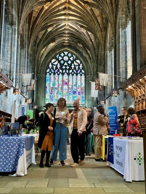 Three people chatting as they walk towards the camera inside Paisley Abbey