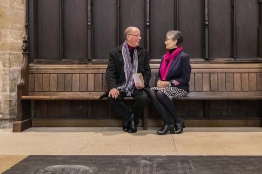 Two people sat on a bench inside a church