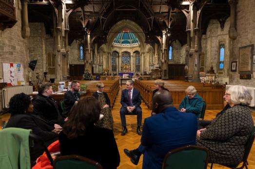 Keir Starmer sits in a circle of people inside a church